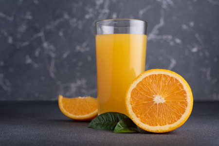 Fresh orange juice in glass with ripe orange fruits on dark backgroundの写真素材