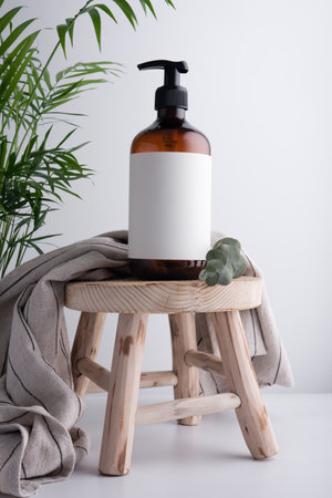 Eco-friendly brown dispenser with shower gel, liquid soap or shampoo on a wooden stool in the bathroomの写真素材