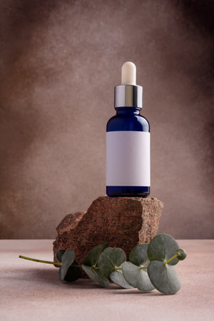 Mockup of skincare cosmetic product. Blue bottle of eco or natural lotion or serum on stone pedestal with eucalyptus branchの写真素材