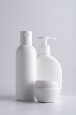 White cosmetic shampoo bottle, lotion dispenser bottle and cream jar mock-up on grey backgroundの写真素材