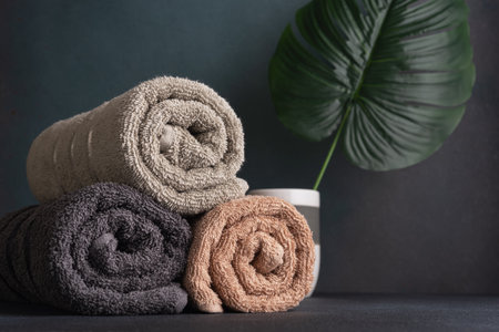 Rolled cotton towels and monstera leaf for decor. Bathroom and wellness still life.の写真素材