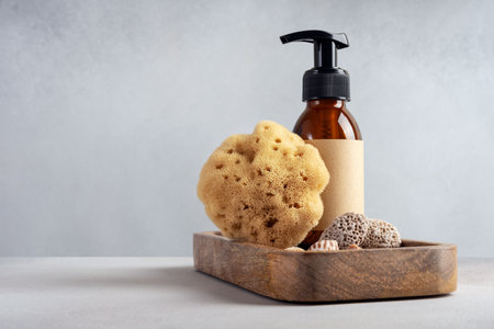 Mock up brown glass bottle and sea natural sponge on a gray background. Bath, spa treatment concept.の写真素材