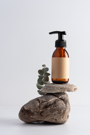 Mock up glass pump bottle on a stone podium on a white gray background. Cosmetology, spa treatment concept.の写真素材