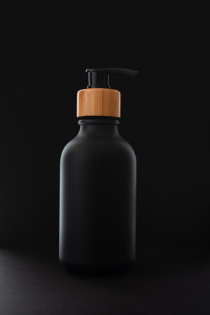 Black bottle with dispenser pump over black background. Blank product packaging mockup template design.の写真素材
