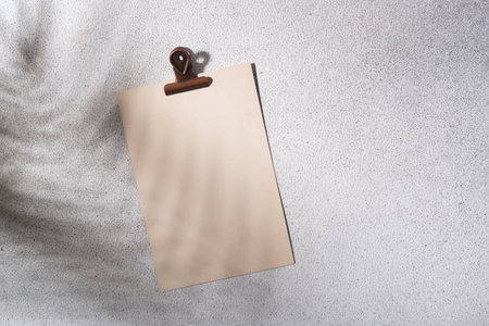 Vintage paper sheet with binder on gray background with palm leaf shadow for mock-upの写真素材
