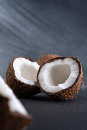 Cracked coconut fruit and whole coconut on dark background