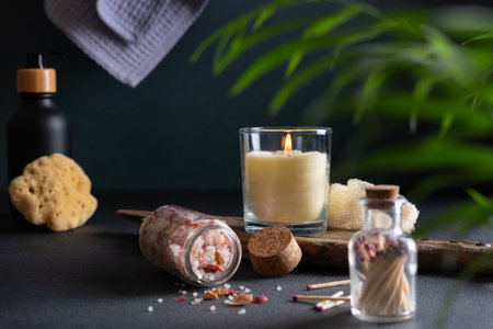 Concept of spa treatment at home. Aroma candle, bath salt and other product for body care. Dark bathroom interior with atmosphere of relax, serenity and pleasure.の写真素材