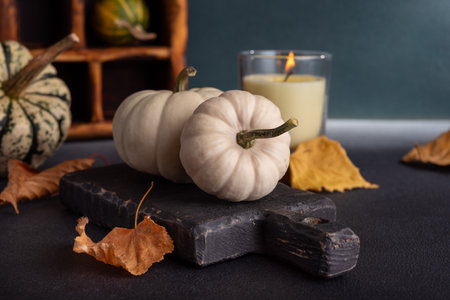 Small decorative pumpkins and glass aroma candle as cozy home decor on dark background for Fall and Thanksgiving holidaysの写真素材