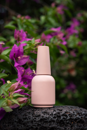 Nail polish pink bottle on stone with buvengelia flowers. Unbranded mockup flowers.の写真素材