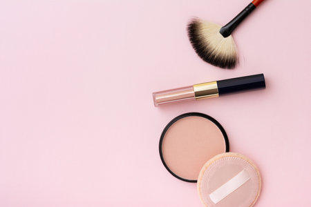 Compact powder, make-up brush, lipstick and sponge, isolated on a pink background. Cosmetic and make-up items.の写真素材