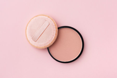 Mineral compact powder and sponge, isolated on a pink background. Cosmetic and make-up items.の写真素材