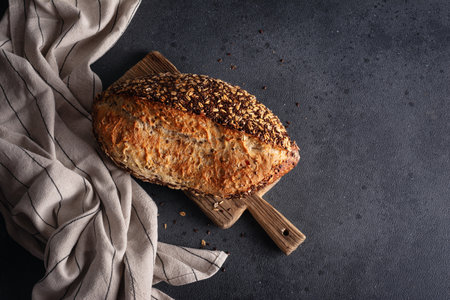Organic homemade whole grain bread on wooden cutting board. Delicious brown bread made from whole grain flour for a healthy dietの写真素材