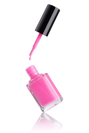 Glass bottle of pink nail polish with flying brush and a drop of enamel falling isolated on a white backgroundの写真素材