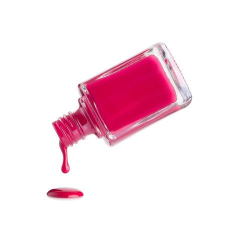 Pink nail polish dripping from a glass bottle isolated on a white backgroundの写真素材