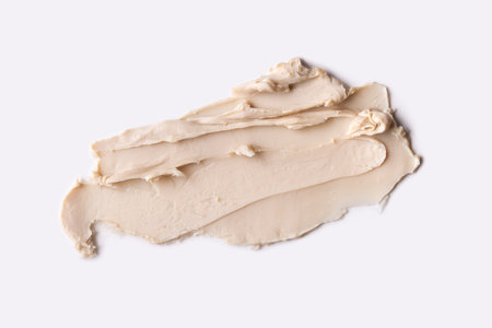 Close-up view of a textured cosmetic clay. Cosmetic product beige texture with visible strokes and ridjes, highlighting its smooth and soft.の写真素材