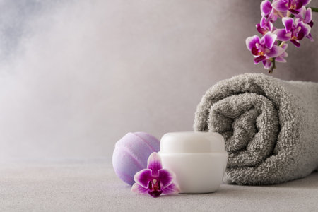White cosmetic cream jar, product mockup on gray background with orchid flower and towel. Face cream...