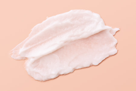 Cosmetic smear of white creamy texture on a beige background. Face cream or body lotion swipe.