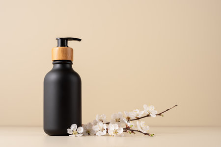 Black dispenser bottle for cosmetic and bath product mock-up with cherry blossom twigの写真素材