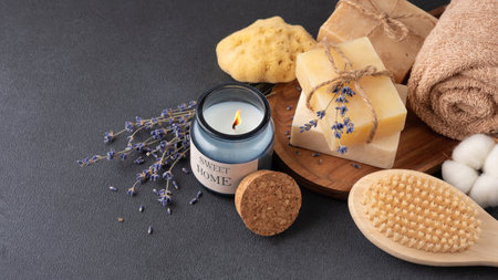 Bathroom items with crafted bars of soap, towel and aroma candle on wooden tray. Spa and selfcare organic product for eco friendly and sustainable lifestyle.の写真素材