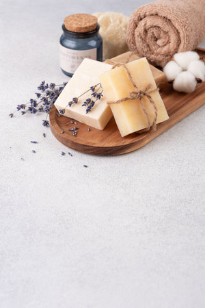 Bathroom items with crafted bars of soap, towel and aroma candle on wooden tray. Spa and selfcare organic product for eco friendly and sustainable lifestyle.の写真素材