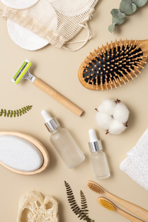 Eco-friendly beauty essentials arranged on a neutral background, featuring a bamboo brush, razor, skincare bottle, and cotton pads. Perfect for wellness, self-care, and sustainable lifestyle themes.の写真素材