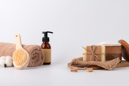 Minimalistic spa setup featuring a rolled towel, wooden back brush, cotton flower, natural soap, and skincare products. Perfect for themes of wellness, relaxation, eco-friendly skincare, and self-care treatments.の写真素材
