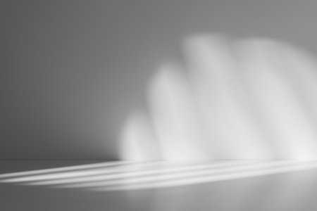 Soft abstract pattern of light and shadows on a smooth gray surface, creating a minimalist and atmospheric background.の写真素材