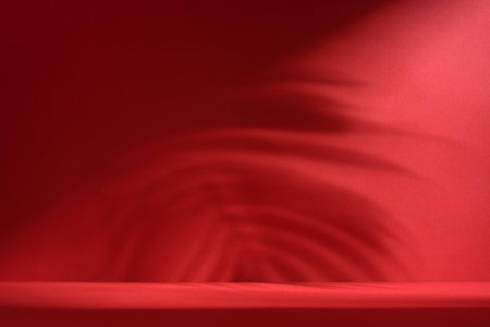 Minimal abstract red background for product presentation with soft shades and light from palm leaves be colored wallの写真素材