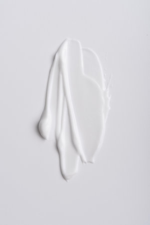 Close-up of white skincare cream smear with smooth texture on a minimalist background. Ideal for beauty, self-care, hydration, and wellness themes, showcasing clean and simple aesthetics.の写真素材