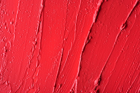 Closeup of red glossy lipstick texture with smooth strokes and rich pigmentation. Vibrant, artistic,...