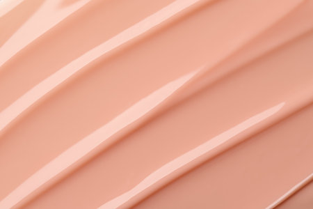Glossy beige cosmetic texture with smooth flowing lines and soft highlights. Nail polish or gel for nail art texture. Abstract skincare product background.の写真素材