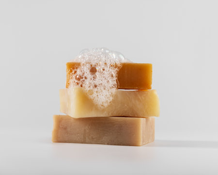 Stack of three handmade natural soap bars with foam and bubbles on a white background. Clean and minimalistic composition. Ideal for eco, skincare, and wellness concepts.の写真素材