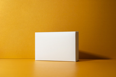 Minimalist white box on golden, yellow background with clean shadows. Perfect mockup for branding, packaging design, product display.の写真素材