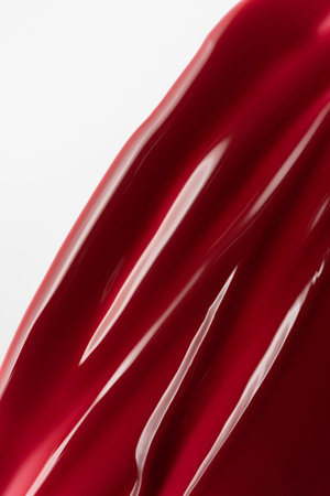 Close-up of glossy red nail gel smear with smooth texture and high shine. Vibrant and elegant cosmetic product background perfect for beauty, fashion, and skincare themes.の写真素材