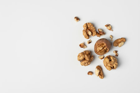 Walnuts and shells on white background. Natural healthy food concept emphasizing organic simplicity, rustic texture, and wholesome nutrition.の写真素材