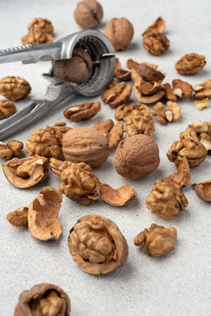 Metal nutcracker with scattered walnut shells. Minimal still life concept of natural food,...