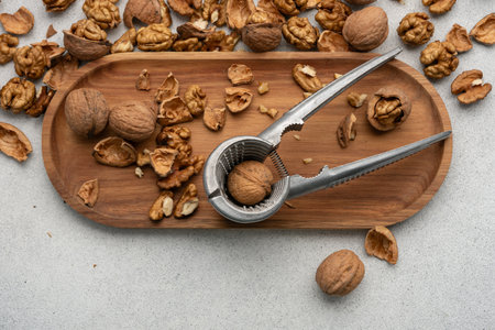 Metal nutcracker with scattered walnut shells. Still life concept of natural food, simplicity, and healthy lifestyle.の写真素材