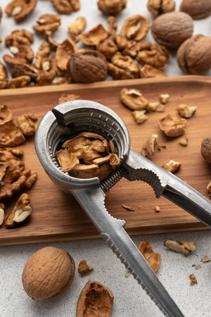 Metal nutcracker with scattered walnut shells. Still life concept of natural food, simplicity, and...