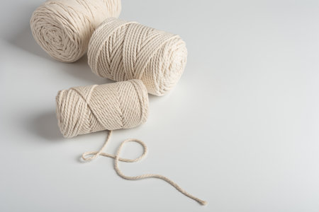 Handmade macrame rope with natural cotton bolls on a clean white background. Rustic craft materials...