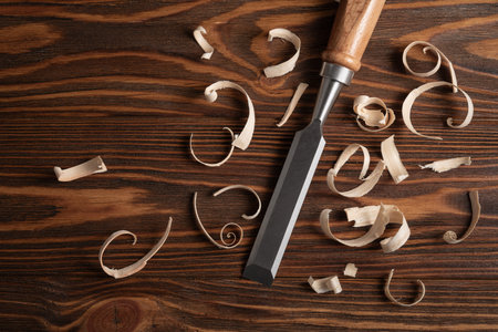 Woodworking chisels with curled wood shavings on a textured board. A detailed artisan craft scene...