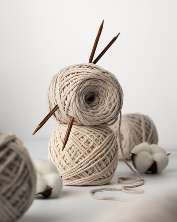 Soft cotton yarn balls with wooden knitting needles and natural cotton bolls on a clean background. Minimalist still life symbolizing handmade craft, calm, creativity and slow living.の写真素材