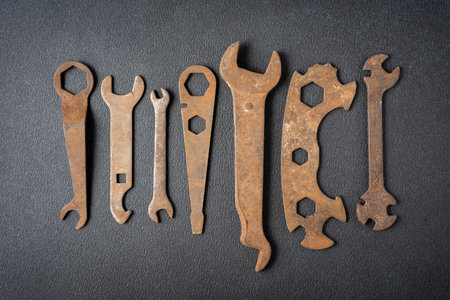 Top view of various rusty wrenches arranged on dark textured background. Industrial repair and maintenance concept with vintage metal tools, corrosion texture and copy space.の写真素材