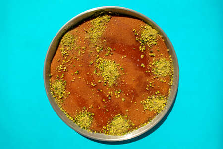 Traditional eastern dessert kunafa in a big aluminium dish isolated on blue background. Top view. Arabic cheese kunafa on blue. Konafa.の写真素材