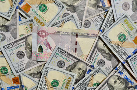UAE national banknote on top of USA national currency, top view of mixed American dollars banknotes. UAE and USA paper money. 500 Dirhams and US dollars exchange rate. USD, AEDの写真素材
