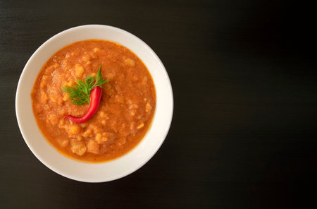 Famous traditional Arabic cuisine - peeled fava beans with chili in white bowl on dark wooden background with copy space. Top view. Foul Mudammas, Egyptian beans.の写真素材