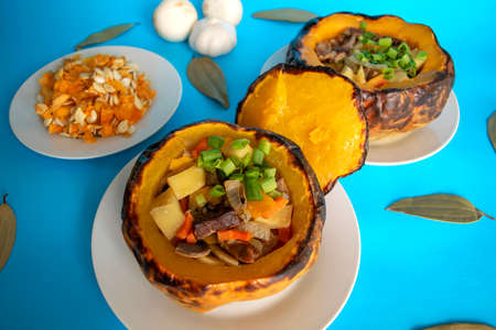 Baked pumpkin stuffed with meat and vegetables on blue background. Beef stew with vegetables in pumpkin. Baked pumpkin foodの写真素材