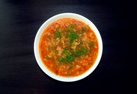Kharcho soup in a white bowl on dark wooden background. Top view. Famous traditional Georgian kharcho soup with beef, rice and tomatoes. Georgian lamb and rice soupの写真素材