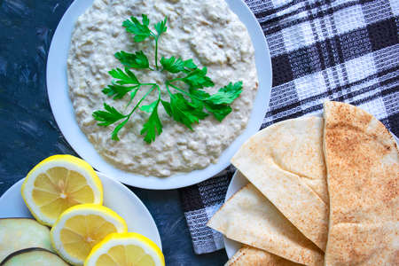 Famous traditional Arabic cuisine - dip Baba ghanoush with pita bread and fresh lemon on grey background. Flat lay, top view. Baba ganoush.の写真素材