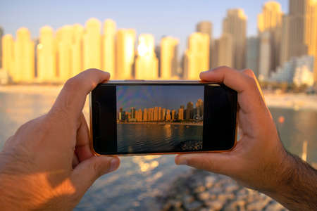 JBR. Panoramic view of Jumeirah Beach Residence skyscrapers through mobile camera. View from the screen and taking picture of Dubai. Man taking photo of beach.の写真素材