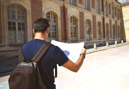 Arab young handsome man with black backpack looks at travel paper map.Traveling along Europe, active...